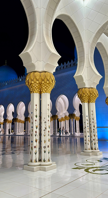 View of ornate columns and arches of the Sheikh Zayed Grand Mosque at night featuring intricate floral inlays and gold leaf details in Abu Dhabi Abu Dhabi United Arab Emirates. View of ornate columns and arches of the Sheikh Zayed Grand Mosque at night featuring intricate floral inlays and gold leaf details in Abu Dhabi Abu Dhabi United Arab Emirates.