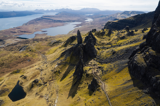 Aerial view of The Storr a dramatic rocky landscape with jagged basalt pinnacles winding hiking trails and distant lochs in Portree Scotland United Kingdom. Aerial view of The Storr a dramatic rocky landscape with jagged basalt pinnacles winding hiking trails and distant lochs in Portree Scotland United Kingdom.