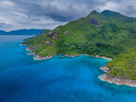 Aerial view of the island s lush verdant mountains meeting the tranquil turquoise sea under a clouded sky Vista do Mar Mahe Island Seychelles. Aerial view of the island s lush verdant mountains meeting the tranquil turquoise sea under a clouded sky Vista do Mar Mahe Island Seychelles.