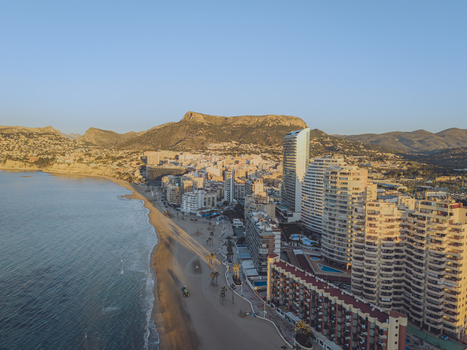 Aerial view of high rise apartment buildings along the sandy beach and the Mediterranean Sea with mountains in the background in Calp Valencian Community Spain. Aerial view of high rise apartment buildings along the sandy beach and the Mediterranean Sea with mountains in the background in Calp Valencian Community Spain.