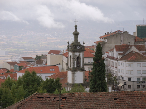 View of Igreja de Nossa Senhora da Conceicao da Covilha with its bell tower rising above the red tiled rooftops of the town under a cloudy sky in Covilha Castelo Branco Portugal.