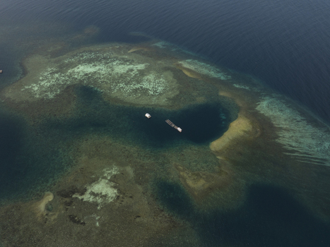 Aerial view of Kanawa Island with vibrant coral reefs shallow turquoise waters and deep blue sea surrounding a floating structure in Kecamatan Komodo Nusa Tenggara Timur Indonesia. Aerial view of Kanawa Island with vibrant coral reefs shallow turquoise waters and deep blue sea surrounding a floating structure in Kecamatan Komodo Nusa Tenggara Timur Indonesia.