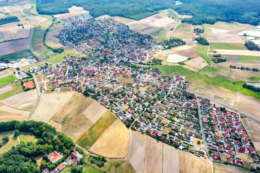 Aerial view of the village of Grossenseebach with its red roofed houses surrounded by agricultural fields and lush green forests Grossenseebach Bavaria Germany.