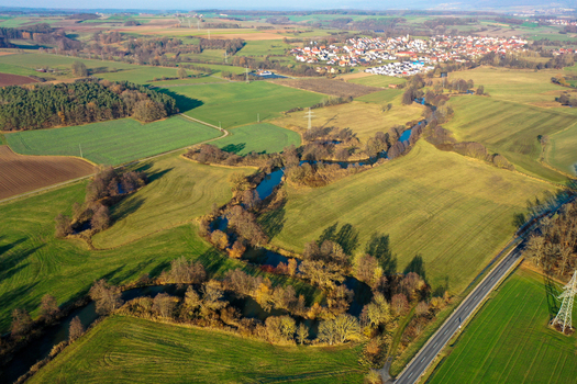 Aerial view of the winding Aisch river along the Aischtalweg surrounded by green meadows and autumn trees near Uehlfeld Bayern Germany. Aerial view of the winding Aisch river along the Aischtalweg surrounded by green meadows and autumn trees near Uehlfeld Bayern Germany.