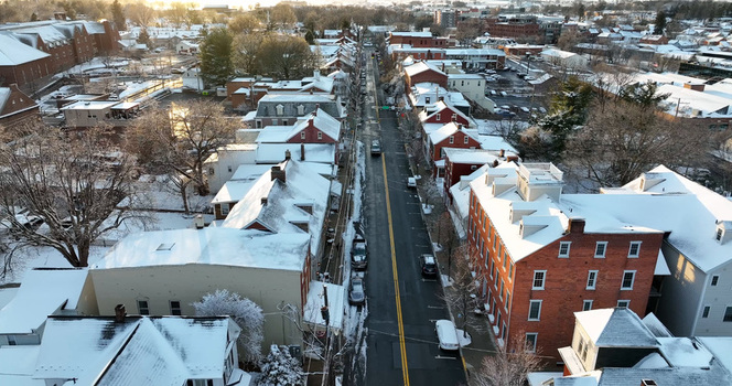 Aerial view of the historic town of Lititz covered in snow featuring brick buildings and residential houses along a quiet street in Lititz Pennsylvania United States.