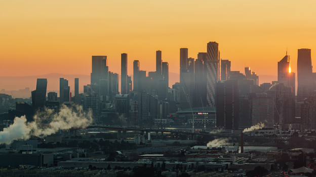 Aerial view of the Melbourne CBD skyline with modern skyscrapers under warm golden hour light and industrial steam in the foreground in Melbourne Victoria Australia.