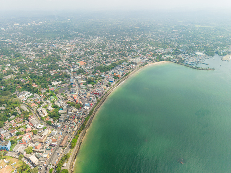 Aerial view of the coastal urban landscape and curved bay with turquoise water and dense buildings in Galle Southern Province Sri Lanka. Aerial view of the coastal urban landscape and curved bay with turquoise water and dense buildings in Galle Southern Province Sri Lanka.