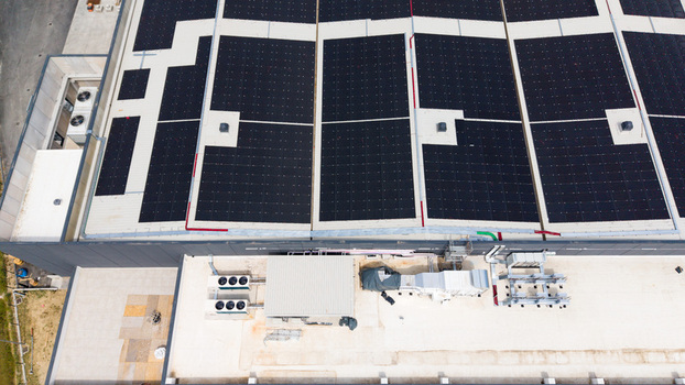 Aerial view of a modern logistics warehouse featuring rooftop solar panels ventilation and cooling systems in Melegnano Lombardy Italy.