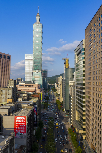 Aerial view of Taipei 101 skyscraper rising above the dense urban landscape of Taipei with bustling traffic on city streets and modern architecture under a clear blue sky in Taipei Taiwan. Aerial view of Taipei 101 skyscraper rising above the dense urban landscape of Taipei with bustling traffic on city streets and modern architecture under a clear blue sky in Taipei Taiwan.