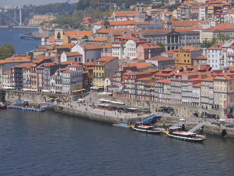 View of the historic Ribeira district in Porto with colorful buildings traditional boats and a waterfront promenade along the Douro River in Porto Porto District Portugal. View of the historic Ribeira district in Porto with colorful buildings traditional boats and a waterfront promenade along the Douro River in Porto Porto District Portugal.