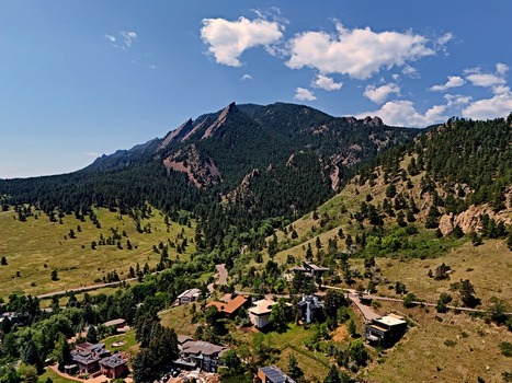 Aerial view of Chautauqua Park and the iconic Flatirons mountain range with lush green slopes and residential homes in the foothills of Boulder Colorado United States. Aerial view of Chautauqua Park and the iconic Flatirons mountain range with lush green slopes and residential homes in the foothills of Boulder Colorado United States.
