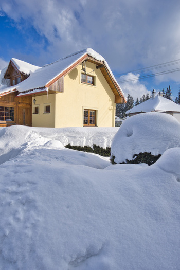 View of a cozy yellow house nestled in a deep blanket of pristine white snow under a bright blue sky in Polianka Donovaly Banskobystricky kraj Slovakia. View of a cozy yellow house nestled in a deep blanket of pristine white snow under a bright blue sky in Polianka Donovaly Banskobystricky kraj Slovakia.