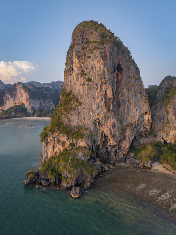 Aerial view of towering cliffs casting long shadows over the turquoise waters of the Andaman Sea Railay Beach Krabi Thailand.