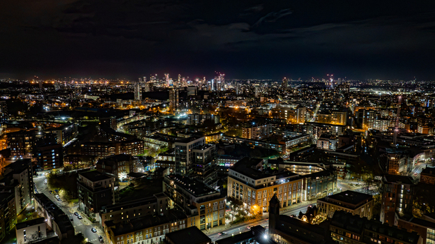 Aerial view of the illuminated London skyline at night featuring dense urban architecture glowing street lights and high rise buildings in London England United Kingdom. Aerial view of the illuminated London skyline at night featuring dense urban architecture glowing street lights and high rise buildings in London England United Kingdom.