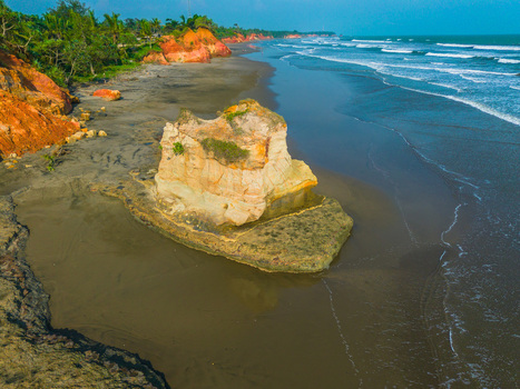 Aerial view of a unique rock formation on a dark sand beach with red cliffs and ocean waves in Bali Bali Indonesia. Aerial view of a unique rock formation on a dark sand beach with red cliffs and ocean waves in Bali Bali Indonesia.