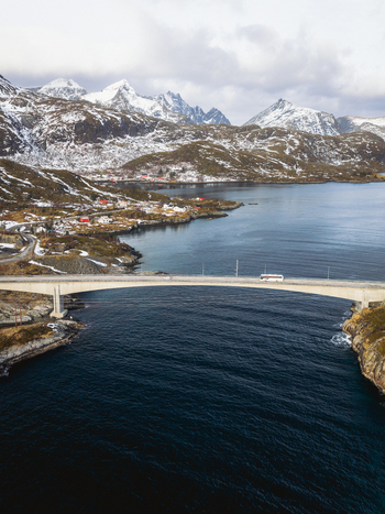 Aerial view of Kåkernbrua bridge stretching across the dark rippling waters connecting the snow dusted islands beneath a sky of soft diffused light Kåkernbrua Nordland Norway. Aerial view of Kåkernbrua bridge stretching across the dark rippling waters connecting the snow dusted islands beneath a sky of soft diffused light Kåkernbrua Nordland Norway.
