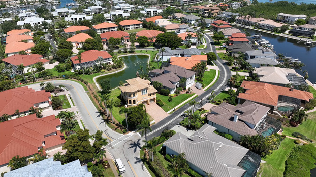Aerial view of a residential neighborhood in Cortez featuring houses with red tile roofs palm trees a small pond and a canal with boats in Cortez Florida United States.