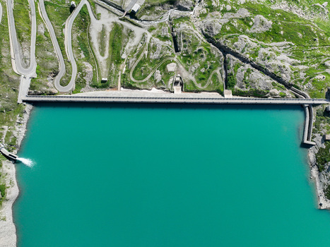 Aerial view of the Serru Lake dam featuring turquoise water and winding mountain roads in the rocky alpine landscape Ceresole Reale Piedmont Italy. Aerial view of the Serru Lake dam featuring turquoise water and winding mountain roads in the rocky alpine landscape Ceresole Reale Piedmont Italy.