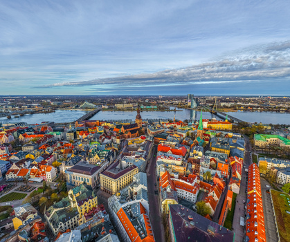 Aerial view of the historic Old Town of Riga with its colorful rooftops the Daugava River and iconic church spires under a bright sky in Riga Latvia. Aerial view of the historic Old Town of Riga with its colorful rooftops the Daugava River and iconic church spires under a bright sky in Riga Latvia.