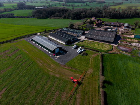 Aerial view of Gnosall Heath farm buildings with agricultural machinery in the field surrounded by green pastures and hedgerows in Gnosall England United Kingdom. Aerial view of Gnosall Heath farm buildings with agricultural machinery in the field surrounded by green pastures and hedgerows in Gnosall England United Kingdom.