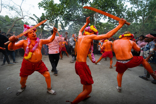 Munshiganj Bangladesh 13 April 2025 View of vibrant orange painted performers with wooden swords captivating onlookers in a spirited cultural display. Munshiganj Bangladesh 13 April 2025 View of vibrant orange painted performers with wooden swords captivating onlookers in a spirited cultural display.