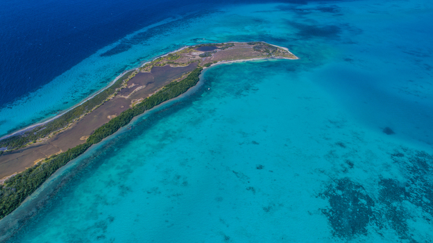 Aerial view of Los Roques archipelago featuring a long island with lush vegetation and salt flats surrounded by vibrant turquoise waters in Los Roques Dependencias Federale Venezuela. Aerial view of Los Roques archipelago featuring a long island with lush vegetation and salt flats surrounded by vibrant turquoise waters in Los Roques Dependencias Federale Venezuela.