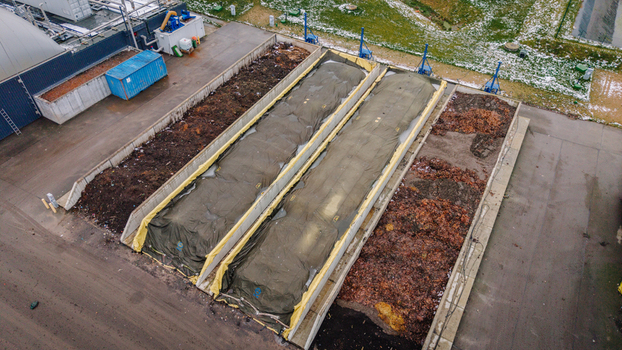 Valmiera Latvija 21 November 2025 Aerial view of a waste management and recycling facility with large composting bays covered by tarps and piles of organic waste in an industrial site.