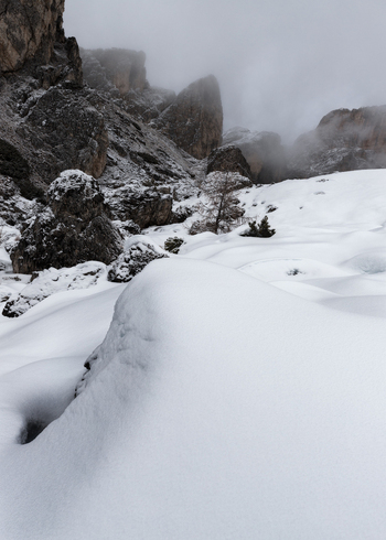 View of the Dolomites mountain range with snow covered rocky peaks partially obscured by thick fog and deep snow drifts in the foreground Trentino Alto Adige Italy. View of the Dolomites mountain range with snow covered rocky peaks partially obscured by thick fog and deep snow drifts in the foreground Trentino Alto Adige Italy.