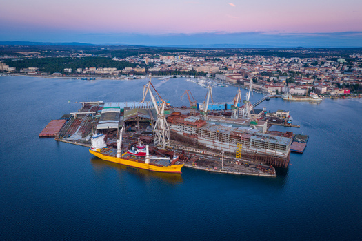Aerial view of Uljanik Shipyard with large industrial cranes ships under construction and workshop buildings situated along the waterfront in Pula Croatia. Aerial view of Uljanik Shipyard with large industrial cranes ships under construction and workshop buildings situated along the waterfront in Pula Croatia.
