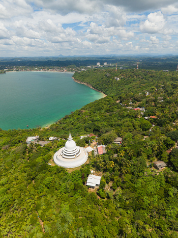 Aerial view of Japanese Peace Pagoda Rumassala surrounded by dense tropical forest overlooking the turquoise waters of the bay in Unawatuna Southern Province Sri Lanka. Aerial view of Japanese Peace Pagoda Rumassala surrounded by dense tropical forest overlooking the turquoise waters of the bay in Unawatuna Southern Province Sri Lanka.