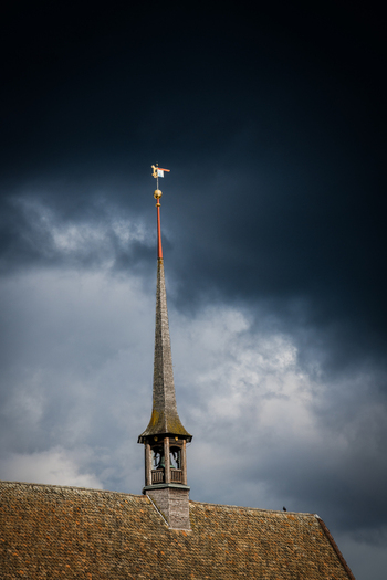 Zurich Switzerland 02 April 2023 View of the Fraumünster Church spire piercing through a dramatic brooding sky its weathered roof a testament to time and history. Zurich Switzerland 02 April 2023 View of the Fraumünster Church spire piercing through a dramatic brooding sky its weathered roof a testament to time and history.