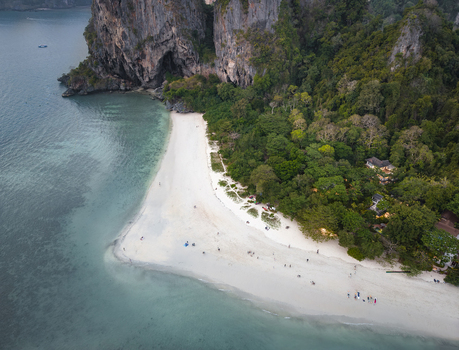 Aerial view of the limestone cliffs meeting the turquoise sea fringed by a pristine beach and verdant forest Krabi Thailand. Aerial view of the limestone cliffs meeting the turquoise sea fringed by a pristine beach and verdant forest Krabi Thailand.