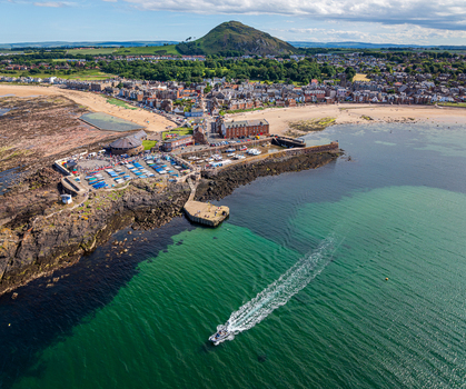 Aerial view of North Berwick harbour with boats moored in the basin the sandy beach and the prominent North Berwick Law hill in the background North Berwick Scotland United Kingdom. Aerial view of North Berwick harbour with boats moored in the basin the sandy beach and the prominent North Berwick Law hill in the background North Berwick Scotland United Kingdom.