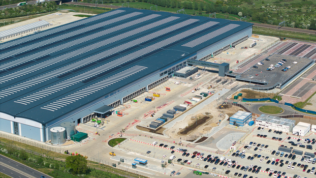 Aerial view of Symmetry Park distribution center featuring a large industrial warehouse with loading bays and parking lots in Kettering England United Kingdom. Aerial view of Symmetry Park distribution center featuring a large industrial warehouse with loading bays and parking lots in Kettering England United Kingdom.