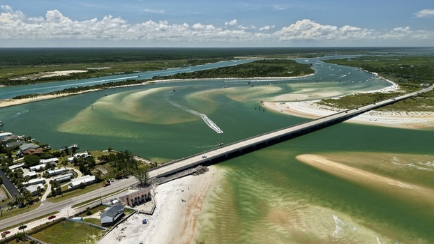 Aerial view of Matanzas Inlet showing the bridge spanning the turquoise waters sandy shoals coastal vegetation and clear blue sky in St. Johns County Florida United States. Aerial view of Matanzas Inlet showing the bridge spanning the turquoise waters sandy shoals coastal vegetation and clear blue sky in St. Johns County Florida United States.