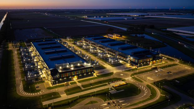 Aerial view of the Microsoft data center illuminated at night with surrounding parking lots roads and agricultural fields in Middenmeer North Holland Netherlands.