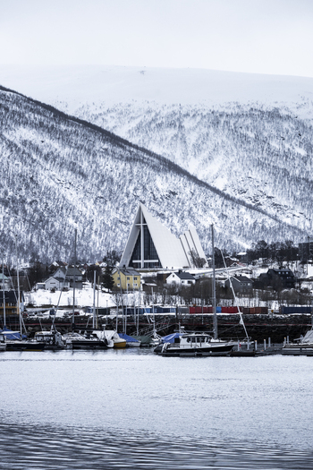 Tromso Norway 07 March 2026 View of the Arctic Cathedral with its distinct triangular architecture harbor with boats and snow capped mountains. Tromso Norway 07 March 2026 View of the Arctic Cathedral with its distinct triangular architecture harbor with boats and snow capped mountains.