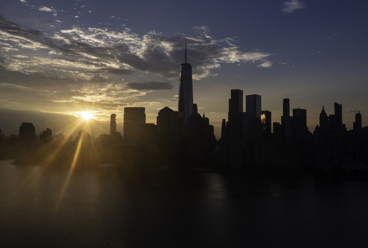 Aerial view of the New York skyline featuring One World Trade Center silhouetted against a vibrant sunset over the water in New York New York United States.