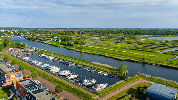 Aerial view of the Oosterdel nature reserve with lush green fields and a marina filled with boats in Broek op Langedijk Noord Holland Netherlands. Aerial view of the Oosterdel nature reserve with lush green fields and a marina filled with boats in Broek op Langedijk Noord Holland Netherlands.