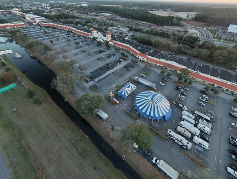 Aerial view of a striking blue and white circus tent amidst a sea of parked vehicles contrasting with the muted tones of the surrounding landscape St. Augustine Florida United States. Aerial view of a striking blue and white circus tent amidst a sea of parked vehicles contrasting with the muted tones of the surrounding landscape St. Augustine Florida United States.