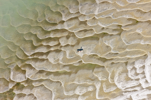 Aerial view of a person standing on the rippled sandy surface of a tidal flat with intricate patterns in Joypurhat Rajshahi Division Bangladesh. Aerial view of a person standing on the rippled sandy surface of a tidal flat with intricate patterns in Joypurhat Rajshahi Division Bangladesh.