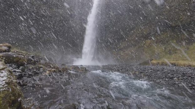 View of a waterfall during a snowstorm in Iceland. View of a waterfall during a snowstorm in Iceland.