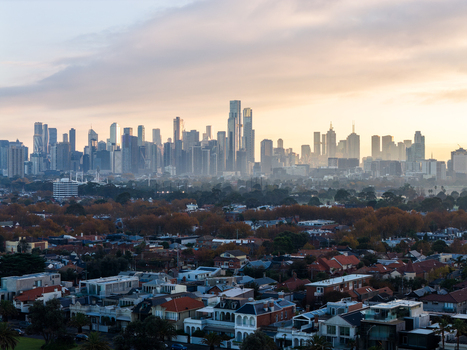 Aerial view of the Melbourne skyline at sunrise with high rise buildings residential rooftops and trees with autumn foliage in Melbourne Victoria Australia. Aerial view of the Melbourne skyline at sunrise with high rise buildings residential rooftops and trees with autumn foliage in Melbourne Victoria Australia.