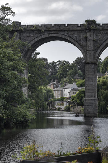 View of the historic Knaresborough Viaduct spanning the River Nidd with lush trees and stone buildings in the background in Knaresborough England United Kingdom.
