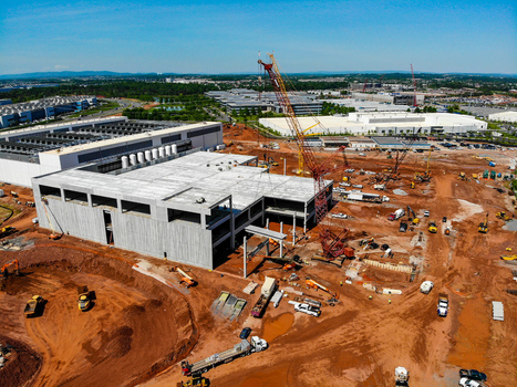 Aerial view of a large industrial construction site with a concrete building structure tall cranes heavy machinery and earthmoving equipment in Ashburn Virginia United States. Aerial view of a large industrial construction site with a concrete building structure tall cranes heavy machinery and earthmoving equipment in Ashburn Virginia United States.