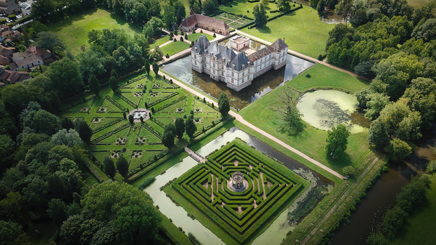 Aerial view of the historic Chateau de Cormatin with its surrounding moat and intricate formal gardens featuring a boxwood maze and geometric patterns in Cormatin Bourgogne Franche Comte France. Aerial view of the historic Chateau de Cormatin with its surrounding moat and intricate formal gardens featuring a boxwood maze and geometric patterns in Cormatin Bourgogne Franche Comte France.