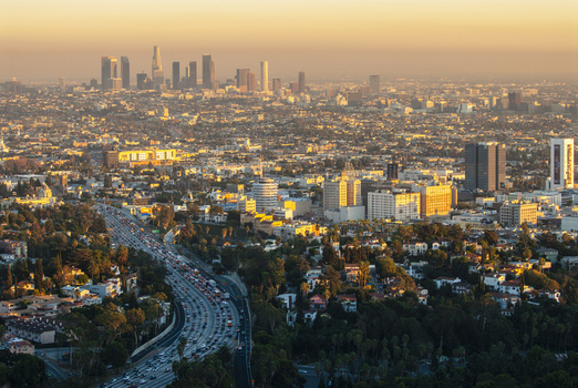 View of the Los Angeles skyline at sunset with dense urban sprawl skyscrapers and a busy freeway filled with traffic in Los Angeles California United States. View of the Los Angeles skyline at sunset with dense urban sprawl skyscrapers and a busy freeway filled with traffic in Los Angeles California United States.