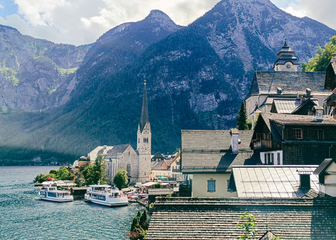 View of the Evangelical Church of Hallstatt with its tall spire traditional houses and boats on the lake set against the Austrian Alps in Hallstatt Upper Austria Austria. View of the Evangelical Church of Hallstatt with its tall spire traditional houses and boats on the lake set against the Austrian Alps in Hallstatt Upper Austria Austria.