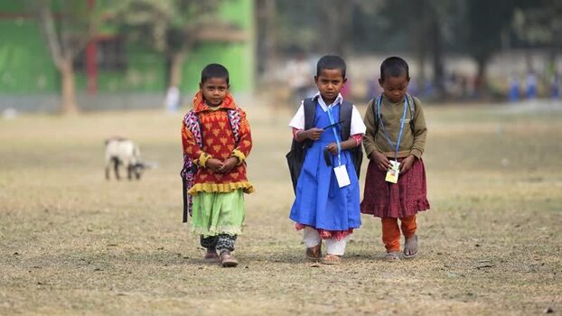View of schoolgirls walking in a field in Bogura Bangladesh.