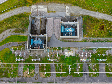 Aerial view of an electrical substation featuring large transformers power lines and grid infrastructure set within a grassy landscape in Andalsnes More og Romsdal Norway. Aerial view of an electrical substation featuring large transformers power lines and grid infrastructure set within a grassy landscape in Andalsnes More og Romsdal Norway.